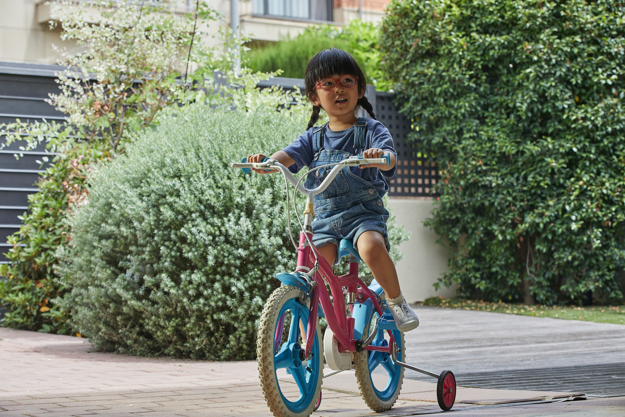 Child wearing glasses rides a bicycle